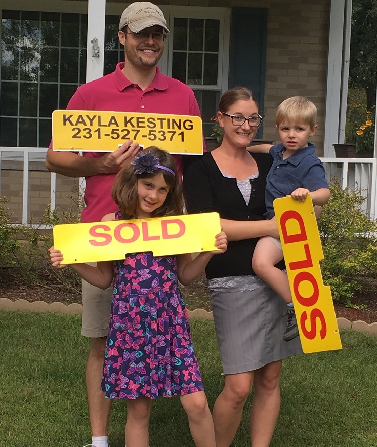 Big Rapids Family Holding Sold Sign